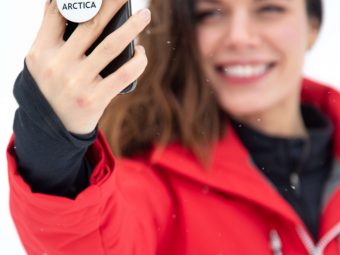 Girl wearing a red Arctica Comp Jacket holding her cell phone with an Arctica PopSocket